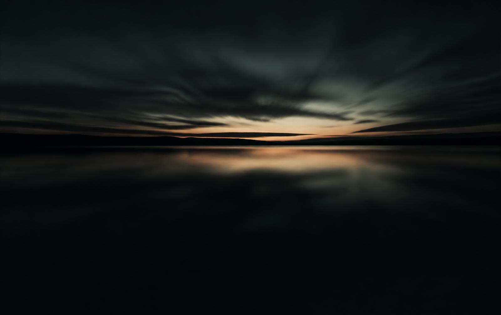 Still water meeting a distant horizon at dusk
